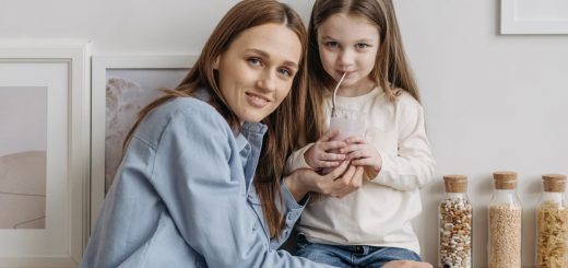 A loving mother with her daughter drinking a smoothie and sharing a warm moment in the kitchen.