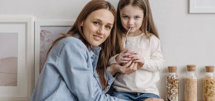 A loving mother with her daughter drinking a smoothie and sharing a warm moment in the kitchen.