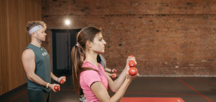 Group of adults exercising indoors with dumbbells, focused on fitness and health.